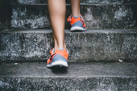 Woman wearing orange and gray shoes running on stairs