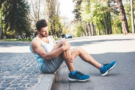 Young runner at the side of the road with leg injury