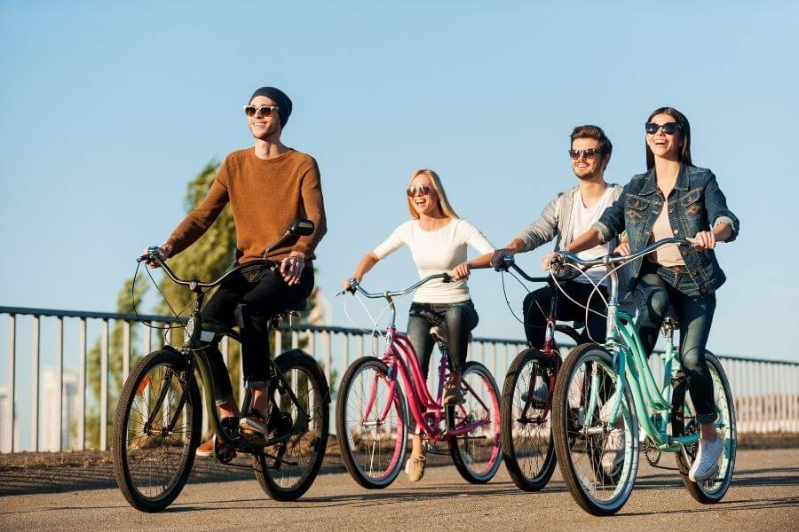 Four young people riding bicycles and smiling - Enjoying their social circle