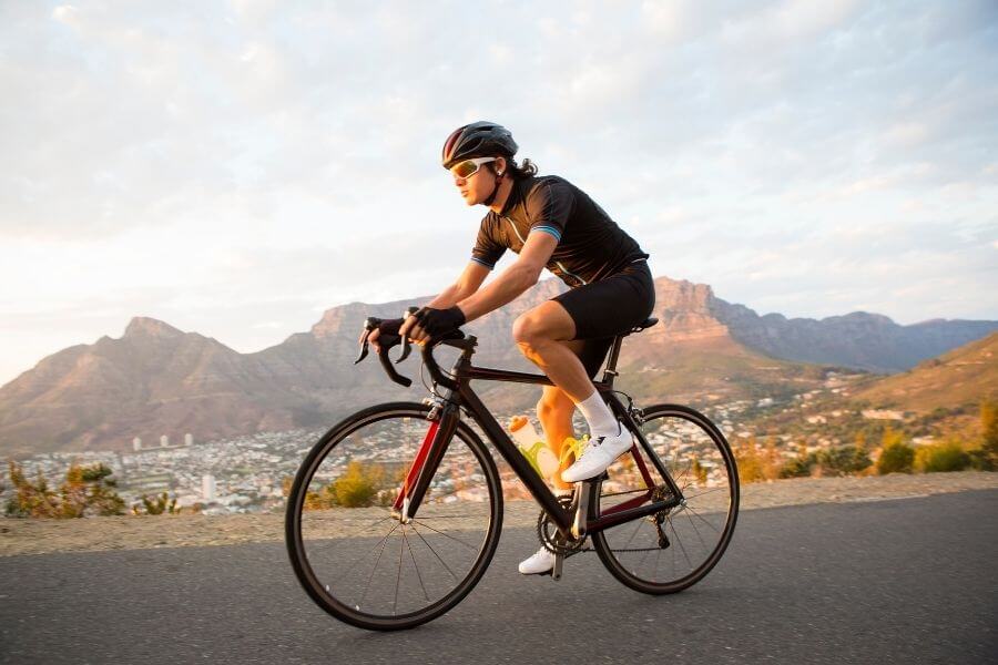 Male cyclist riding a bicycle alone on the road early morning - Doing a low impact sport