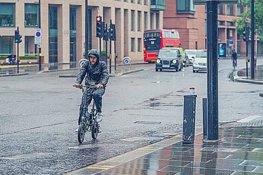 man commuting by bike in the rain