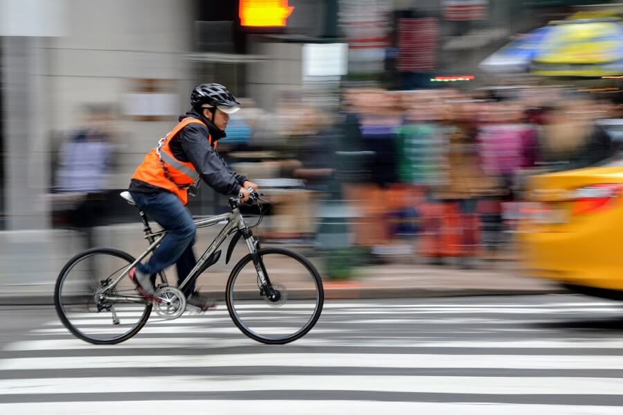Man riding a bicycle wearing bright neon orange reflector vest
