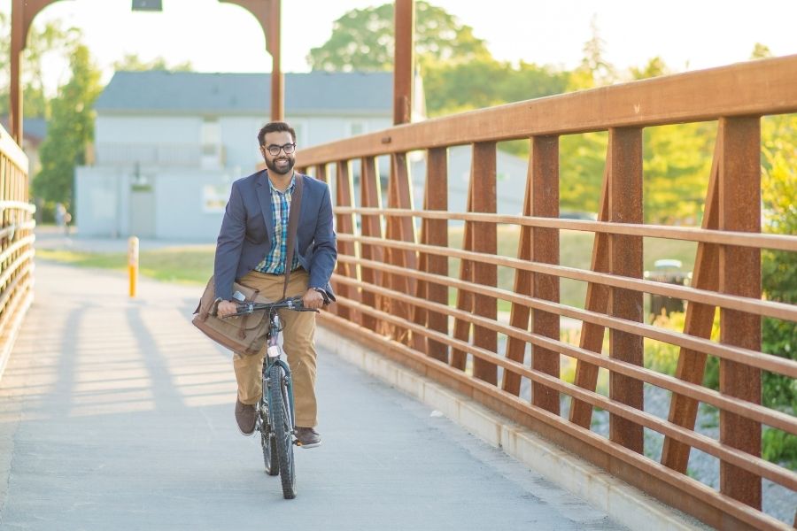 Happy office employee riding a bike on bridge commuting to work