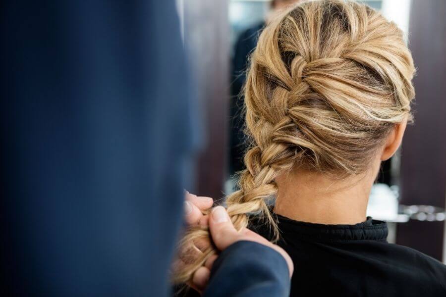 hairdresser braiding client's hair in katniss slanted braid style