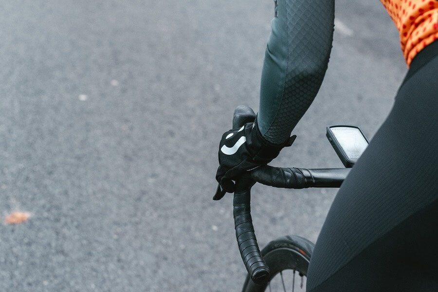Cyclist with black cycling gloves riding bike on road