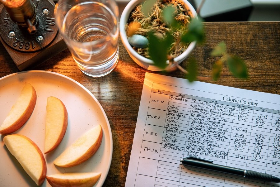 Calorie list on top of table with apples and water on the side