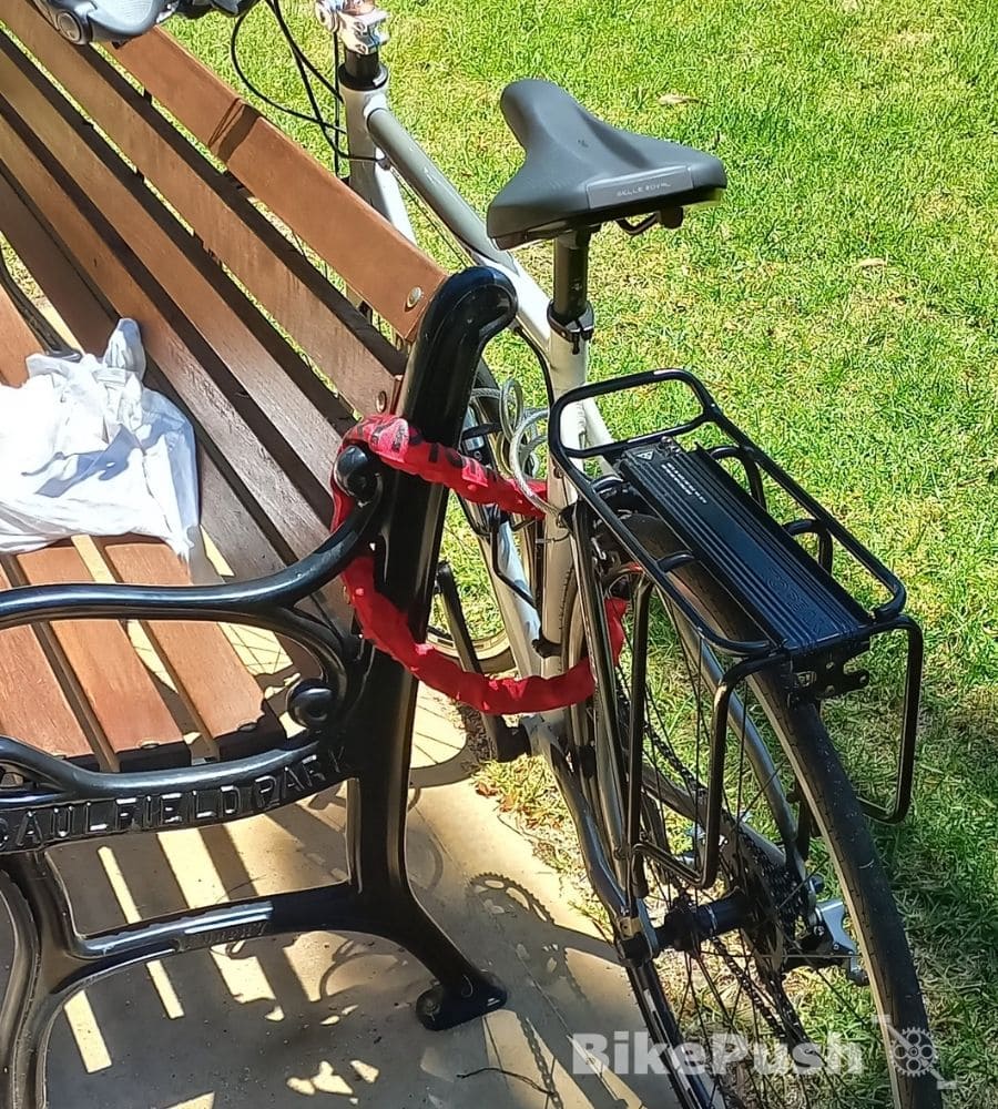 A bike locked to a public seat bench