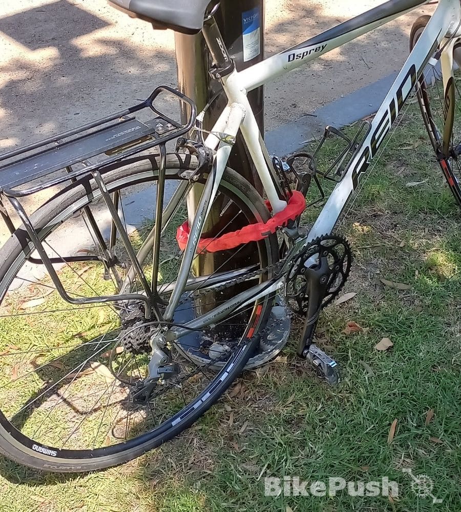 Bicycle locked to a lamppost with a red chain lock