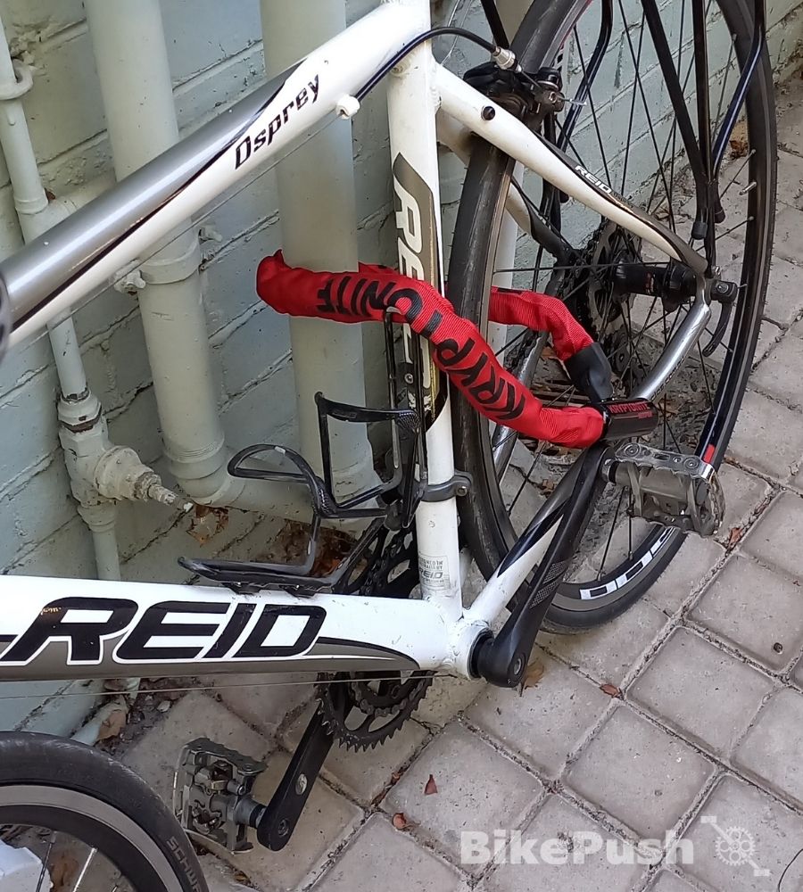 Red lock locking bicycle to a drainpipe
