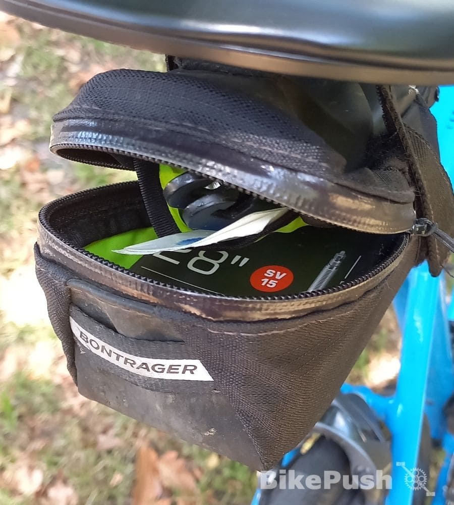 Saddle bag on bike with the zipper open and tools showing inside
