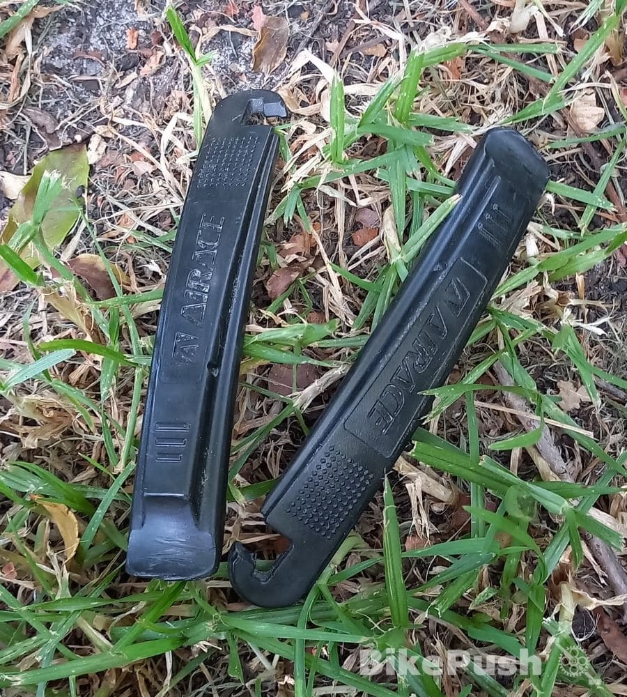 Two Black tyre levers sitting on the grass