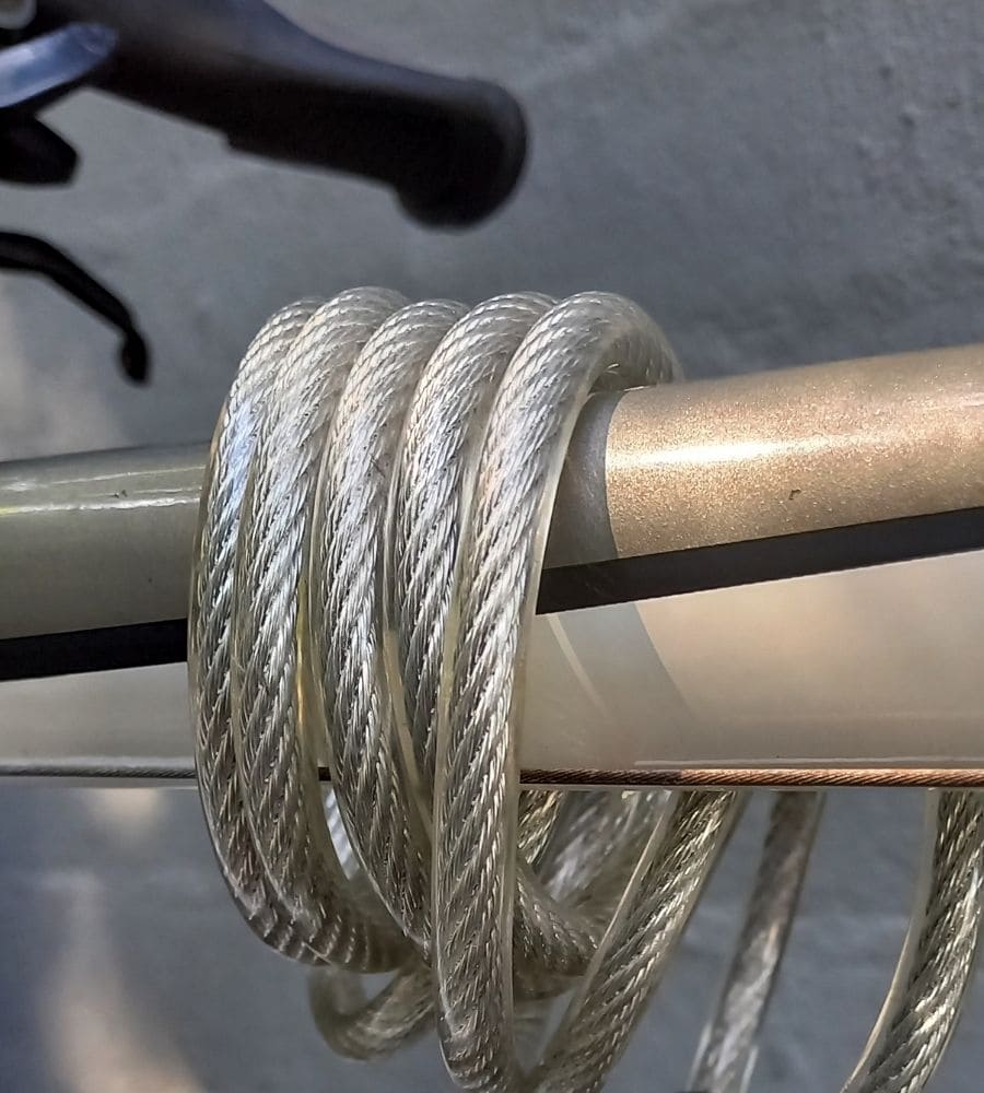 close up view of cable lock wrapped around bicycle top tube and rear brake cable